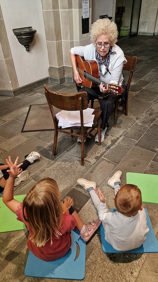 Kinder hören Gitarre und Gesang zu