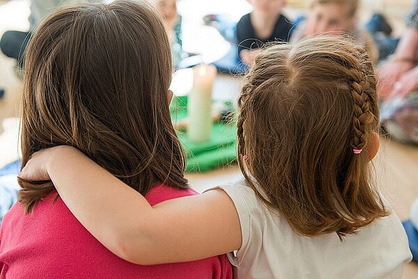Kinder umarmen sich an den Schultern