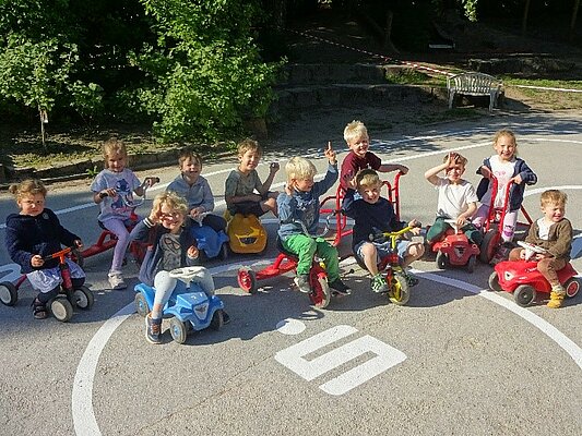 Kinder sitzen auf dem Boden und zeigen neue Straßenbemalung