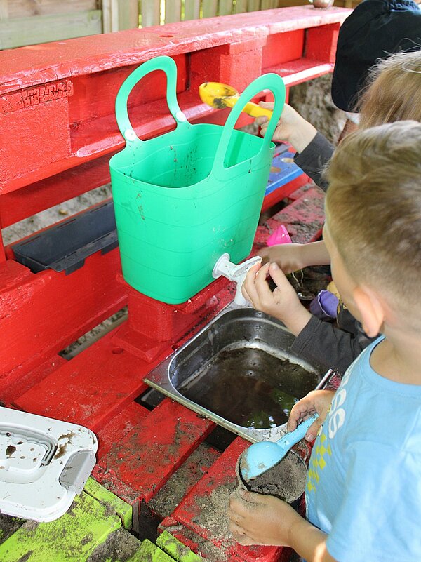 Kind experimentiert an Matschküche