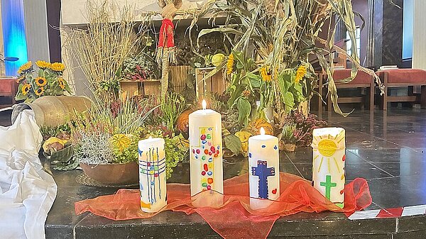 selbstgestaltete Kerzen auf dem Boden vor dem Altar