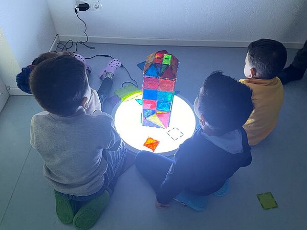 Kinder sitzen auf dem Boden und spielen mit Licht und Schatten