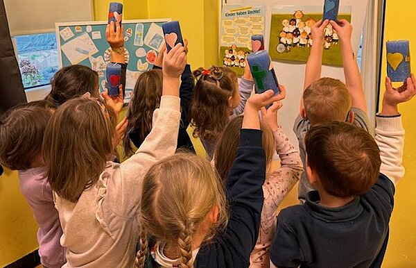 Kinder strecken blaue Kerzen in die Höhe