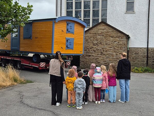 Kinder empfangen den LKW, der den Bauwagen für die Naturgruppe liefert