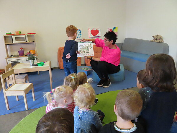 Erzieherin zeigt Kind eine Info-Karte zum Thema Brandschutz