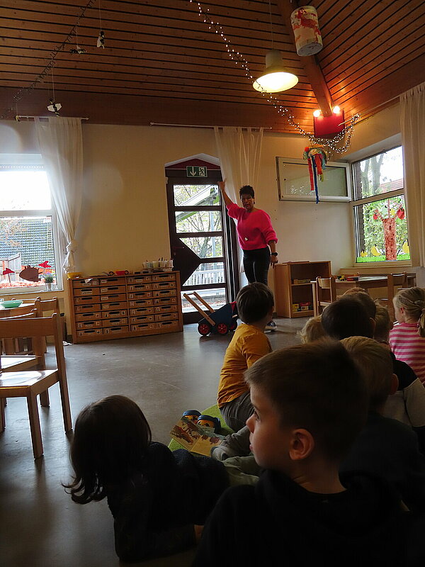 Erzieherin zeigt auf Notausgangschild und Kinder gucken dabei zu