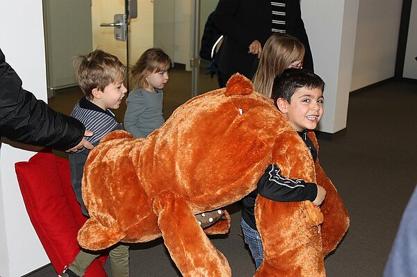 Kinder tragen Teddy in die KiTa