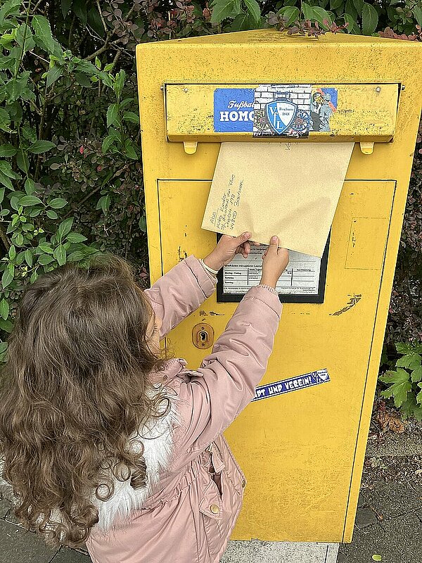 Kind wirft Brief in Briefkasten