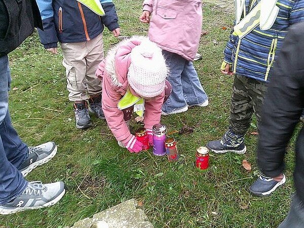 Kinder zünden Kerzen auf dem Friedhof an
