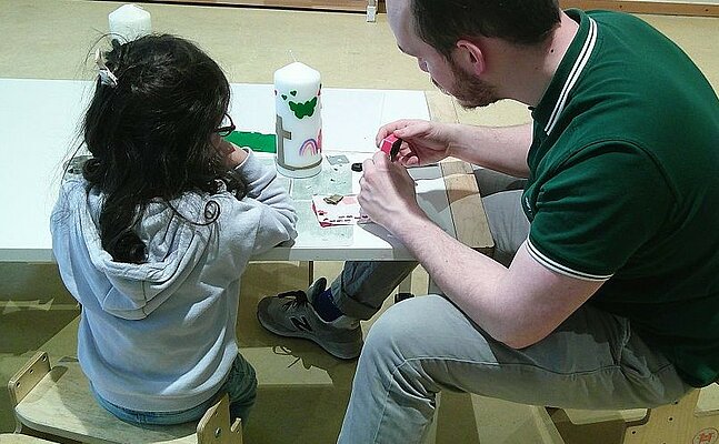 Kind und Erwachsener gestalten Osterkerzen