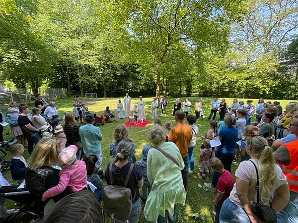 Menschenmenge feiert in der Natur Gottesdienst.