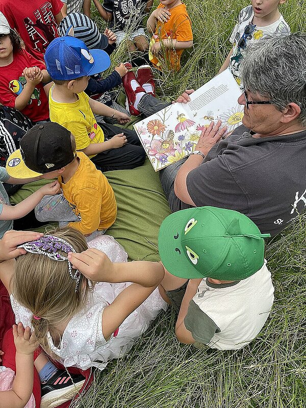 Erzieherin liest Kindern aus Bienenbuch vor