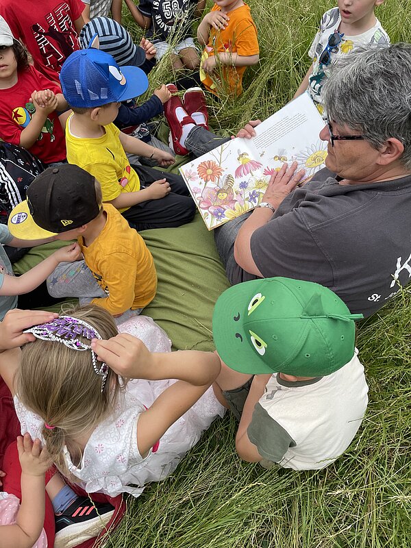 Erzieherin liest Kindern aus Bienenbuch vor
