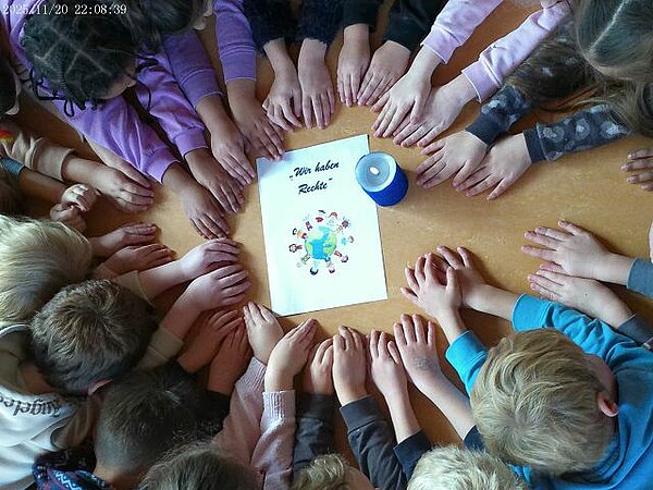 Kinderhände zeigen auf blaue Kerze