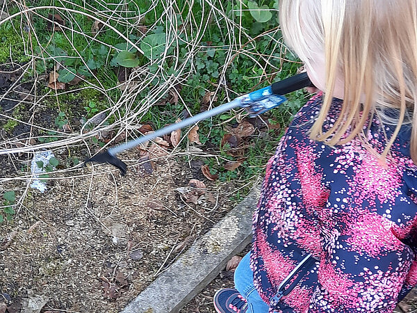 Kind sammelt Müll auf