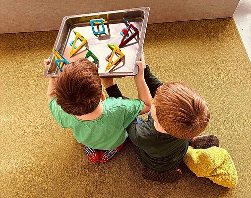 Kinder bauen eine Kugelbahn mithilfe eines Backbleches