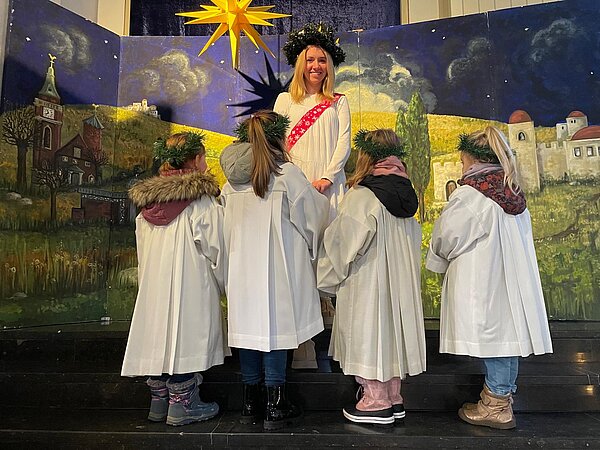 4 Kinder stehen um eine als Lucia verkleidete Frau
