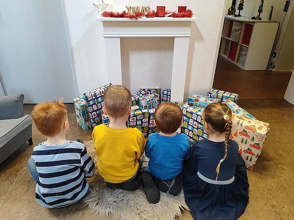 Kinder sitzen vor Geschenken