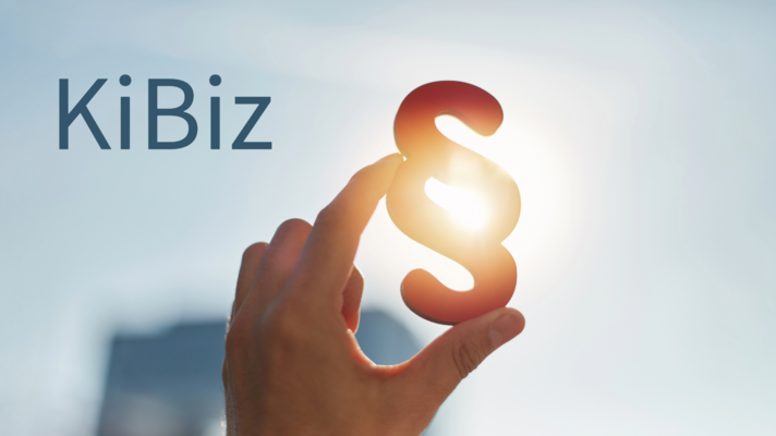 Eine Hand hält einen Paragraphen zwischen Zeigefinger und Daumen.