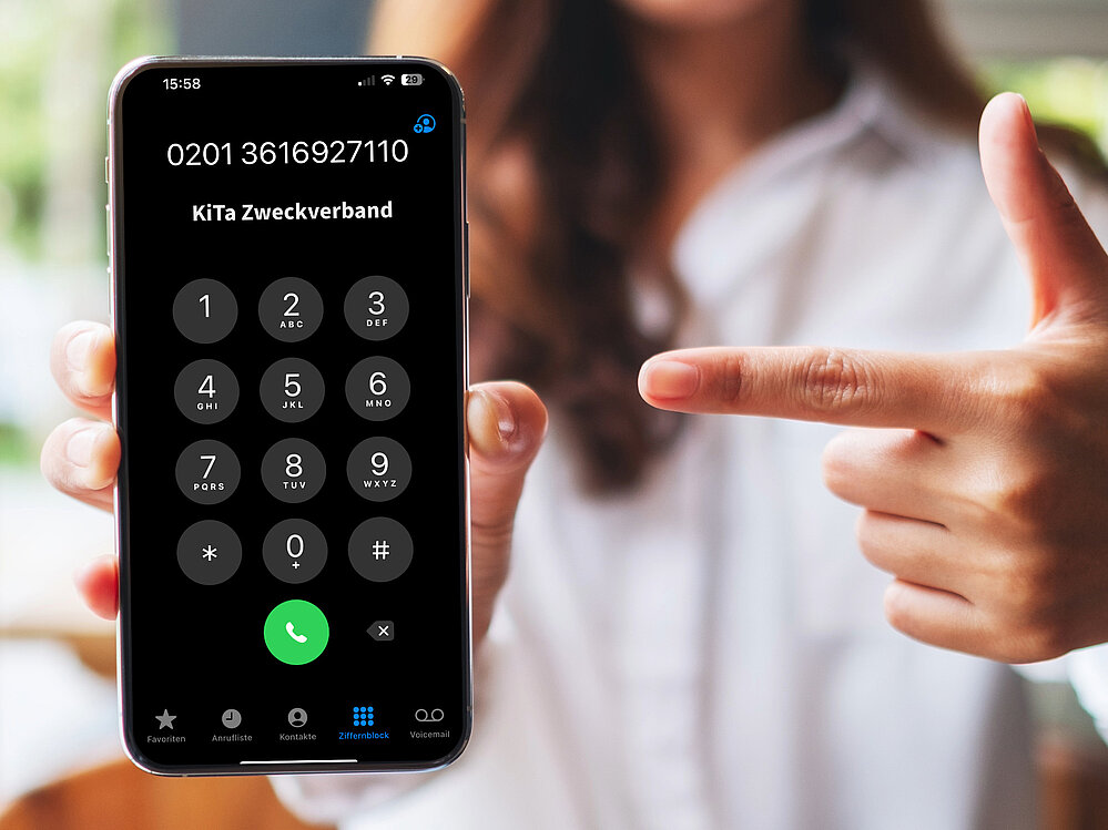 Hand zeigt auf Smartphone mit neuer Telefonnummer
