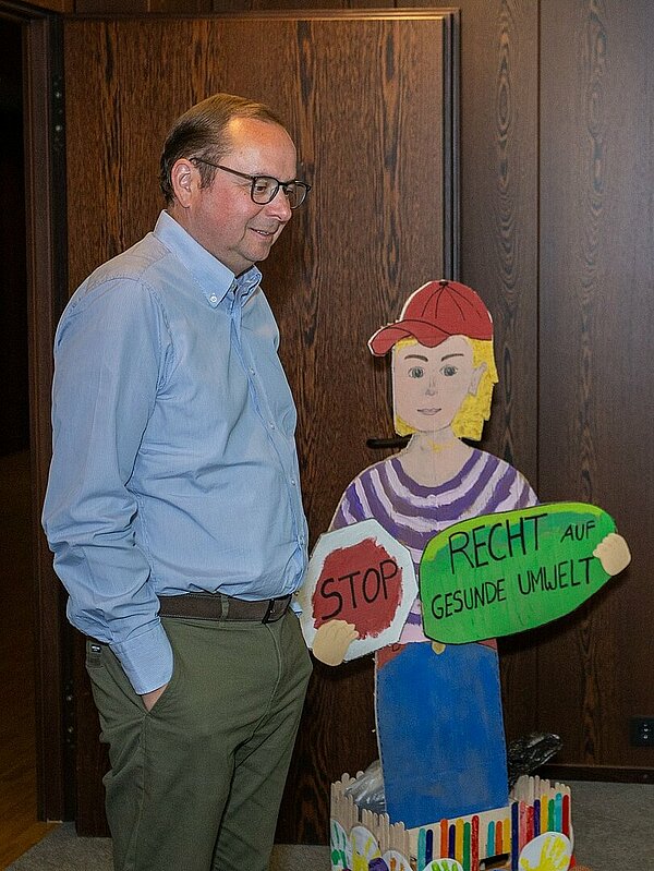 Die Kinder pr&auml;sentieren Thomas Kufen ihre selbstgestaltete Pappfigur, die Besucher*innen &lrm;des Rathauses auf das Recht auf eine gesunde Umwelt hinweisen soll. &lrm;